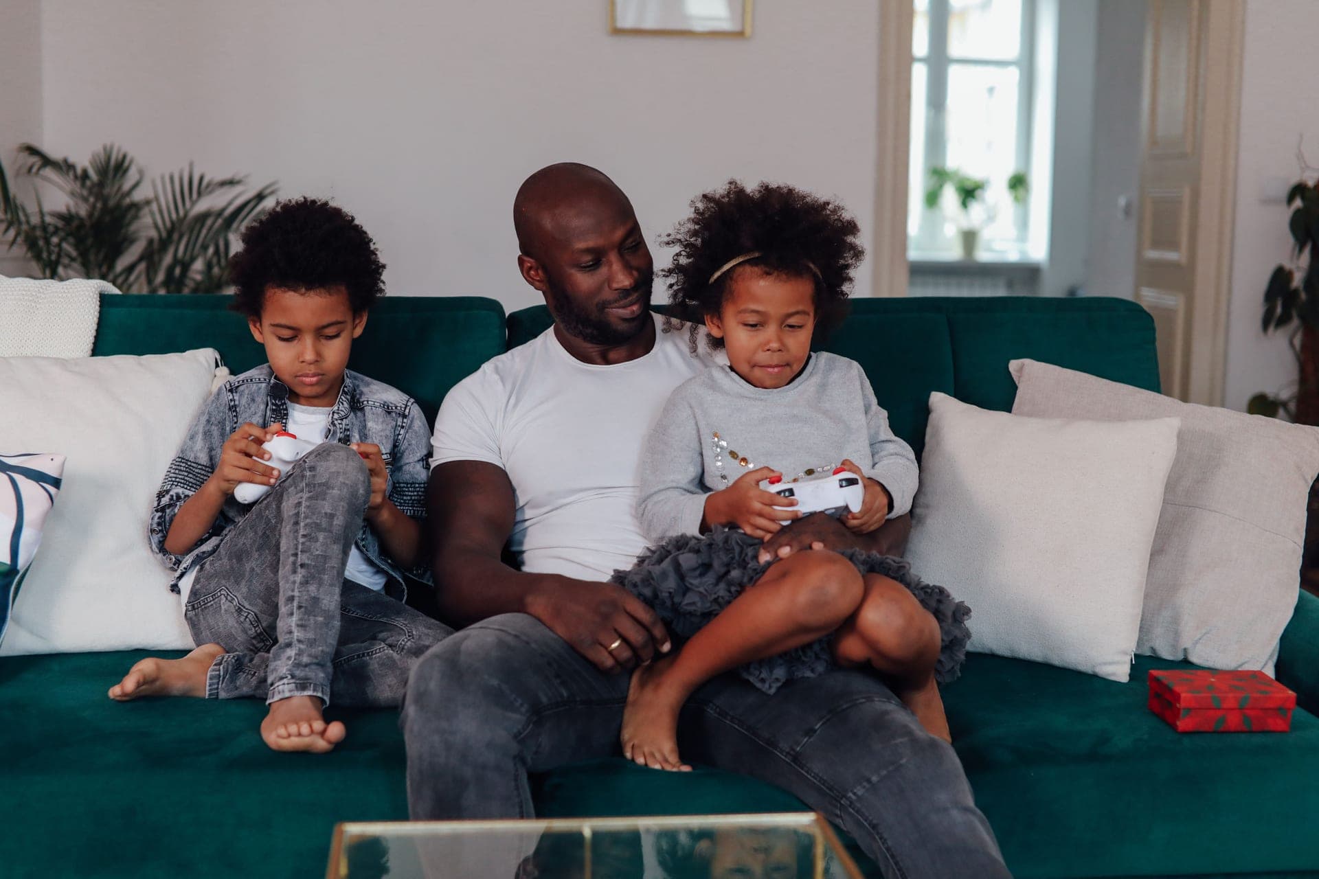 A parent and children playing a video game together in a bright living room