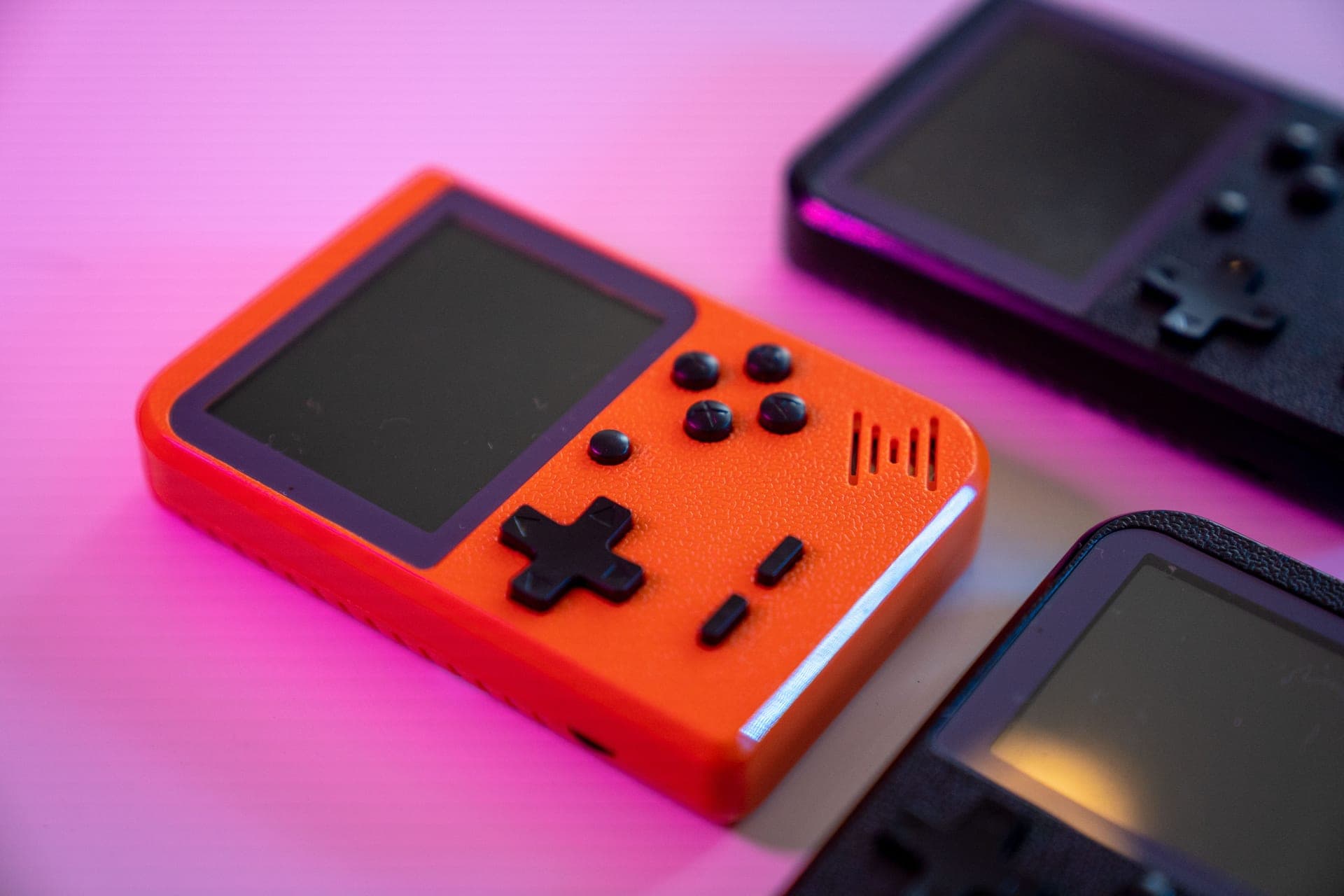 A handheld game console held in two hands against a warm background
